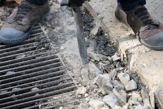 Male workers use electric concrete breaker for digging and drilling concrete repairing driveway surface with jackhammer at the local city road, during sidewalk, work construction site.