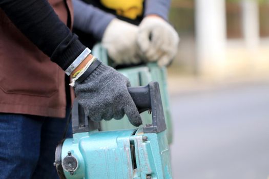 Male workers use electric concrete breaker for digging and drilling concrete repairing driveway surface with jackhammer at the local city road, during sidewalk, work construction site.