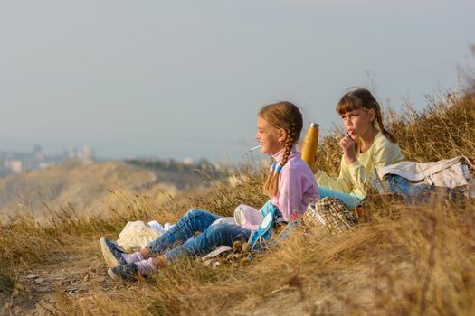 Children on a picnic drink water and eat sweets