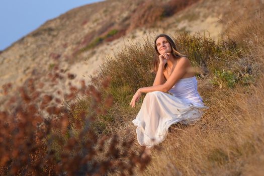 A girl in a white dress enjoys a beautiful view of the sunset