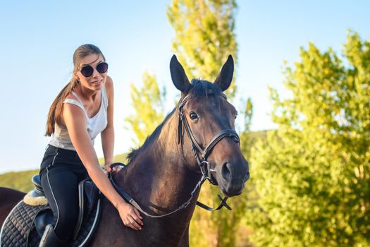 Girl with glasses strokes a horse on a horse ride