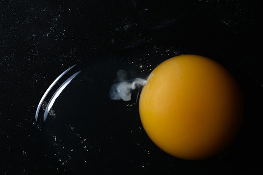 Broken Raw Egg Yolk on Dark Stone Background.