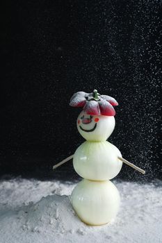 A snowman made of pearl onions stands on a snow