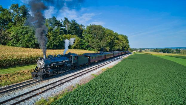 Aerial View of a Restored Antique Steam Engine and Passenger Cars Steaming Up at a Small Rail Road Station on a Summer Day