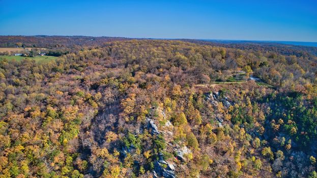 Aerial View of a Rocky Hill side with Autumn Trees on a Cloudless Blue Sky