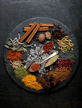 Powder spices on spoons in black wooden table background.