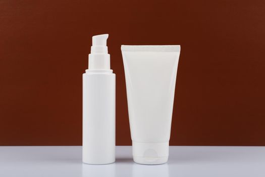 Horizontal still life with two white cream tubes on white table against dark brown background. Concept of male skincare with copy space. High quality photo