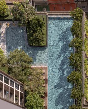Bangkok, Thailand - 08 Jan 2021 : Top down aerial view of outdoor swimming Pool surrounding palms and green garden in the beautiful condominium. Modern landscape architecture with swimming pool.