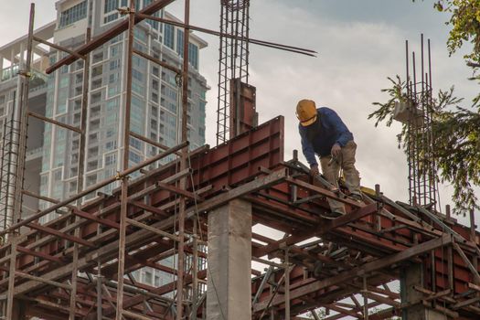 Construction Worker Welding soldering metal girders and Sparks in a Structure high above at the Construction site. Selective focus.