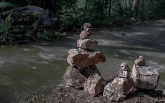 Balanced stone tower on walkway up the mountain with green plants in the background. No focus, specifically.