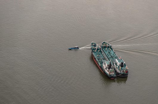 Bangkok, Thailand - 04 Jan 2021 : Aerial view of Two Cargo Ship and Small Ferry Boat in the Chao Phraya River at evening. Selective focus.