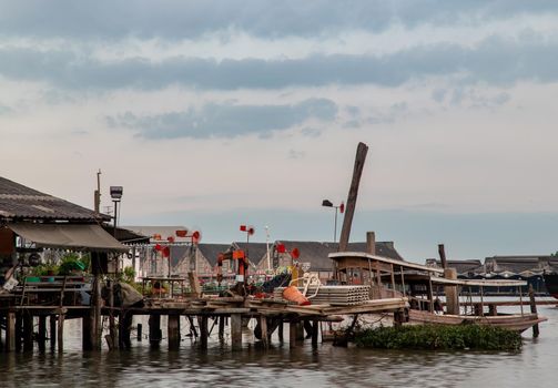 Bangkok, Thailand - 04 Jan 2021 : Small Ferry Boat parked in front of the old riverfront wooden house at Chao Phraya river. Selective focus.