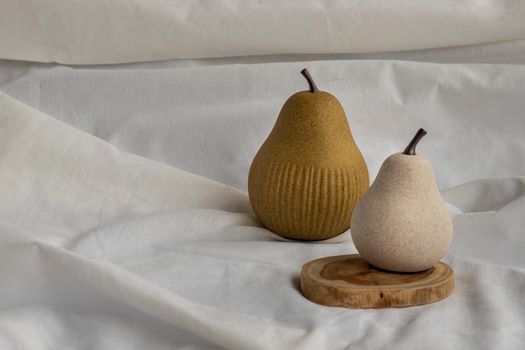 Two ceramics pear fruits on white fabric background. Ceramic tableware, Home decor.