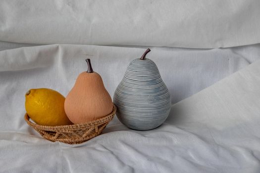 Two ceramics pear fruits and Lemon fruits on white background. Ceramic tableware, Home decor, Copy space.
