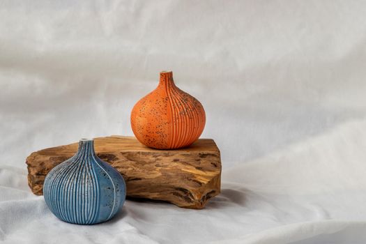 Two beautiful small ceramic vases with wooden logs on white background. Ceramic tableware, Home decor.