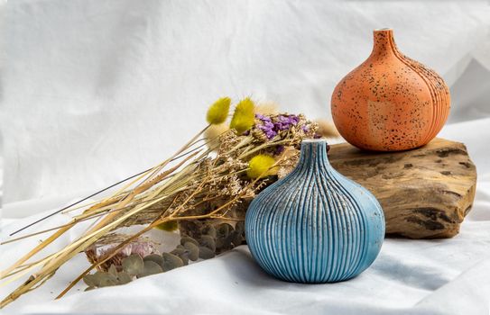 Two beautiful small ceramic vases with wooden logs on white background. Ceramic tableware, Home decor.
