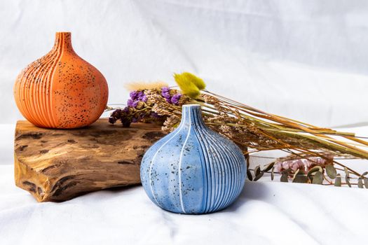 Two beautiful small ceramic vases with wooden logs on white background. Ceramic tableware, Home decor.