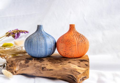 Two beautiful small ceramic vases with wooden logs on white background. Ceramic tableware, Home decor.