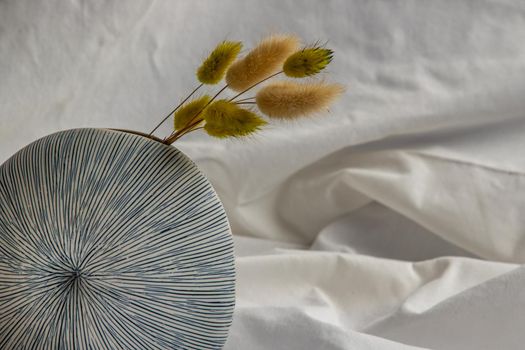 Close-up of Dried flowers in Handmade Ceramic Vase on White background. Home decor, Space for text.