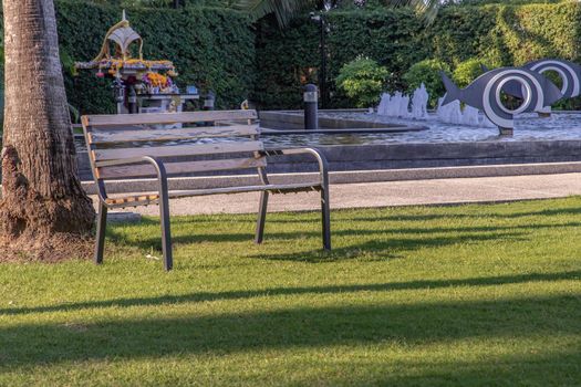Wooden benches on grass floor in a shady area of the park. Seating and unwind area. Selective focus.