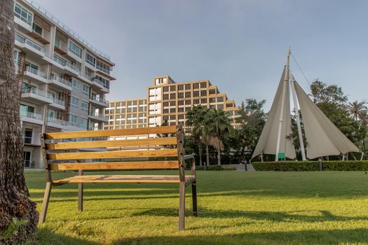 Wooden benches on grass floor in a shady area of the park at Condominium. Seating and unwind area. Selective focus.