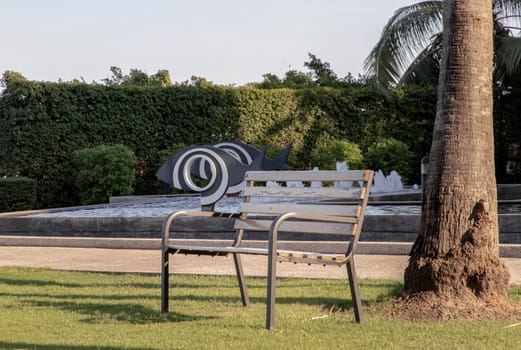 Wooden benches on grass floor in a shady area of the park. Seating and unwind area. Selective focus.