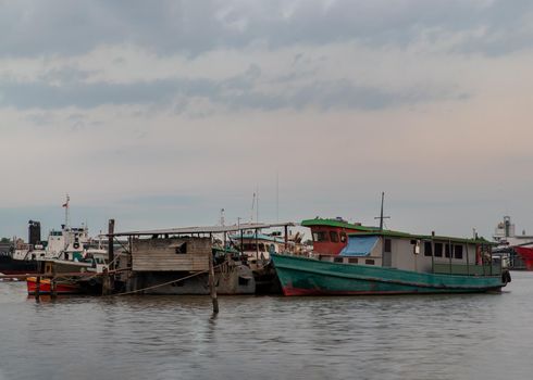 Bangkok, Thailand - 04 Jan 2021 : A small cargo ship parked in front of the small pier at Chao Phraya river. Selective focus.