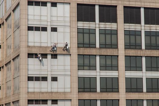 Group of workers cleaning windows service on high rise office building. Selective focus.