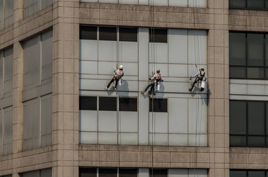 Group of workers cleaning windows service on high rise office building. Selective focus.