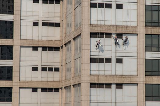 Group of workers cleaning windows service on high rise office building. Selective focus.
