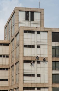 Group of workers cleaning windows service on high rise office building. Selective focus.