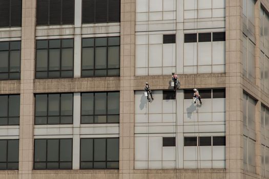 Group of workers cleaning windows service on high rise office building. Selective focus.