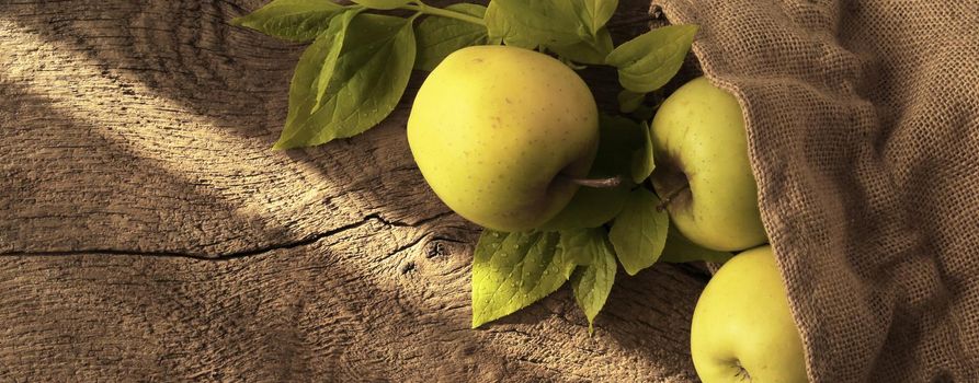 Rustic autumn kitchen, green yeallow apples, morning light on old wooden background