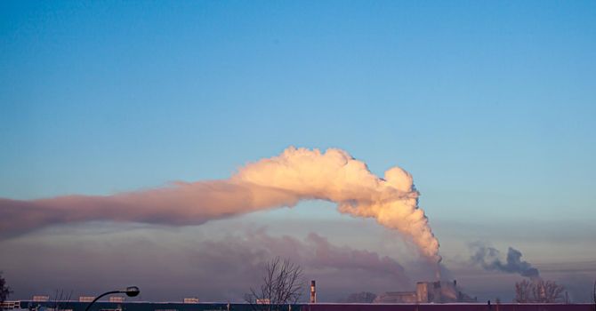 White thick smoke from the boiler room chimney. Smoke against the blue sky. Air pollution. Heating of the city. Industrial zone.