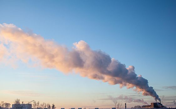 White thick smoke from the boiler room chimney. Smoke against the blue sky. Air pollution. Heating of the city. Industrial zone.