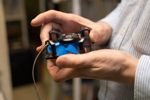 cooler, fan from the computer with the bearing open for repair and lubrication in the hands of the master of the service center