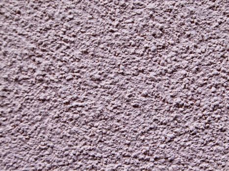 The textured rough surface of the plastered wall of the house is lilac in color.Texture or background