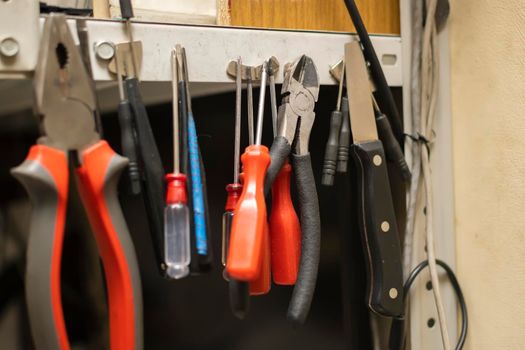 a set of different old worn out tools hang on magnets on a metal rack in the service center