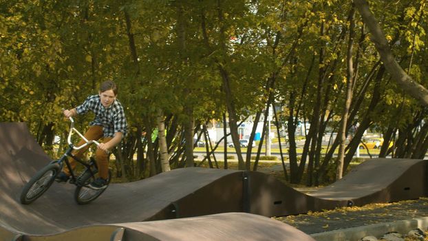 Young boy, biker riding on the pump track in the park at sunny day. Childrens sport and healthy lifestyle concept