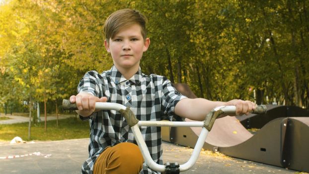 Portrait of young biker sitting on the bike in the park at sunny day. Childrens sport and healthy lifestyle concept