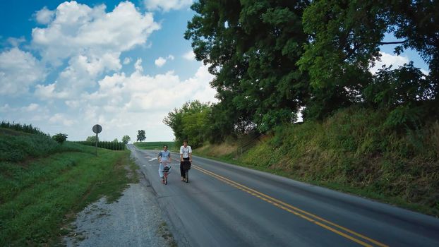 Ronks, Pennsylvania, July 2020 - Two Amish Teenagers One Boy and One Girl on Scooters on a Summer Day