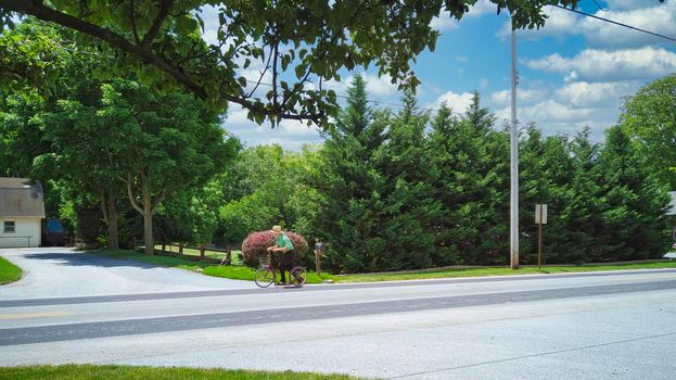 An Amish Boy Riding His Scooter on a Country Road on a Beautiful Summer Day