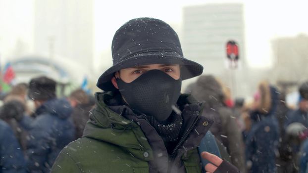 Close up portrait of a man wearing special protective mask on background of the rally crowd. Coronavirus epidemic in Moscow. Concept of health and safety life. COVID-19 pandemic