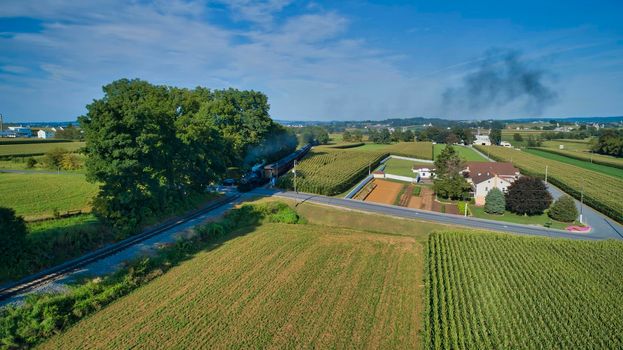 Aerial View of a Restored Antique Steam Engine and Passenger Cars Passing a Crossing in the farm Fields on a Summer Day