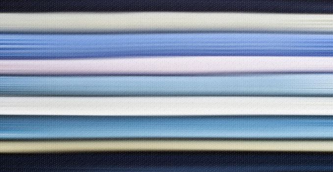 Layers of sweaters, cloth fabric in pastel colour. Cosy winter warm wool clothing stacked in pile close-up