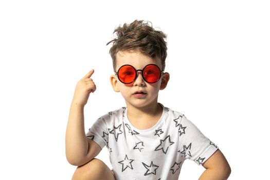 Little caucasian boy in red glasses points thumbs up isolated on white background.