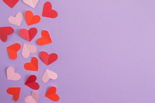 Valentine's Day background. Pink and red hearts on a pastel purple background. Valentine's Day concept. Layout for postcards and congratulations. Flat lay, top view, copy space