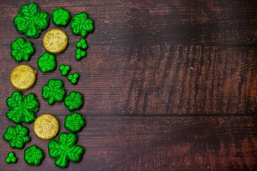 Glitter Covered Four Leaf Clovers for Saint Pattys Day Filling Half the Frame on a Wooden Background
