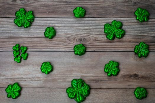 Glitter Covered Four Leaf Clovers for Saint Pattys Day in a Diagonal Pattern on a Wood Background