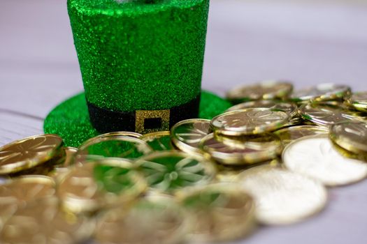 A Green Glitter Covered Saint Pattys Day Hat With Gold Coins in Front of It